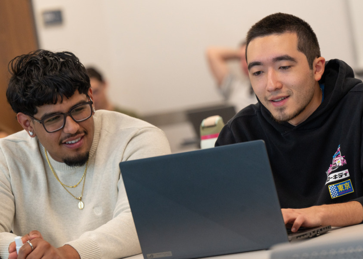 two students sitting sharing a laptop